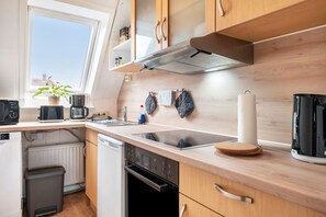 Et moderne køkken med indbygget ovn, kaffemaskine og elkedel.