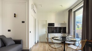 Eine moderne Küche mit Essbereich, einer Couch und Blick ins Freie.