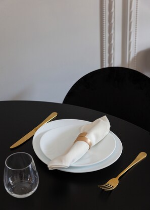 A table set with white plates, a folded napkin, a clear wine glass, and gold-colored cutlery. - Helvetia 32 (Baveno)