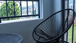 Een balkon met een ronde tafel en een frame stoel, met uitzicht op een stadsgezicht.