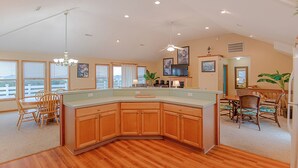 Una cocina amplia con una isla grande, armarios de madera y una zona de comedor con sillas y una mesa.