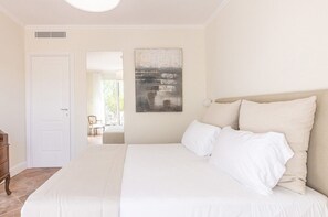 Ein Schlafzimmer mit einem großen Bett, einer weißen Tür und einem Gemälde an der Wand.