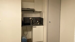A compact kitchen with white cabinets, a black countertop, and a small sink. - Quiet, well-located studio apartment on the edge of the Garonne River (Toulouse)