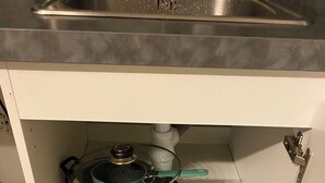 A kitchen with a stainless steel sink, a white cabinet with two shelves, and a white countertop above. - Quiet, well-located studio apartment on the edge of the Garonne River (Toulouse)