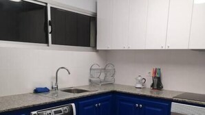 Uma cozinha compacta com máquina de lavar, pia, armários e fogão.