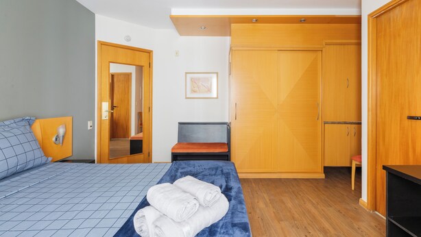 Una camera da letto con un letto, una panca, un armadio e uno sgabello.