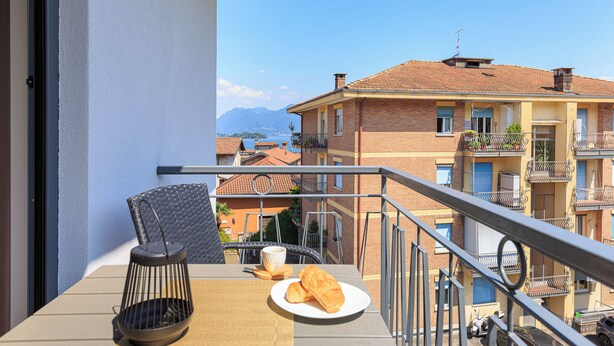 Un balcone con un tavolo, una sedia, un piatto con croissant e una tazza.