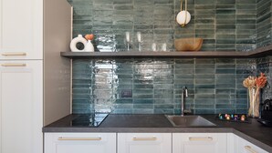 Una cucina con mobili bianchi, un piano di lavoro scuro e un backsplash in piastrelle verdi.