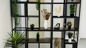 Una sala de estar moderna con una estantería negra que contiene varias plantas y objetos decorativos.