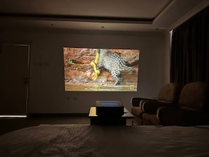A room with a large screen displaying a leopard, a sofa, and a coffee table. - Addis Home & Comfort (Addis Ababa)