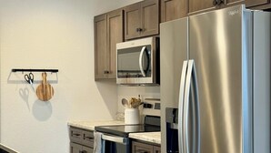 Une cuisine moderne dotée d’appareils électroménagers en acier inoxydable, de meubles en bois et d’un plan de travail en marbre.