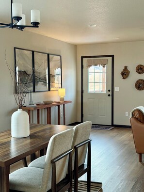 A dining area with a wooden table, two chairs, a vase, and a lamp. - Ridge View Retreat! 2 bed, 2 bath with View and Garage (Rapid City)