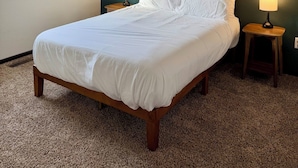 Une chambre à coucher avec un grand lit, deux lampes fixées au mur et deux tableaux accrochés au mur.