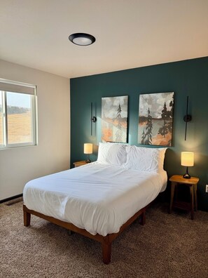 A bedroom with a large bed, two wall-mounted lamps, and two paintings on the wall. - Ridge View Retreat! 2 bed, 2 bath with View and Garage (Rapid City)