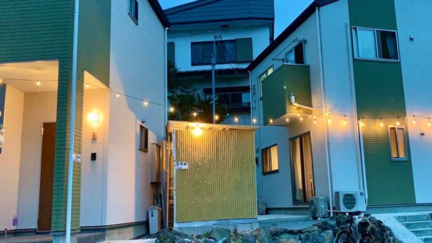 Un immeuble résidentiel comprenant plusieurs logements, décoré de guirlandes lumineuses et doté d’une entrée abritée.