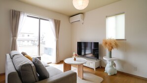 Un salon moderne avec un canapé, un téléviseur, une petite table et un vase décoratif.