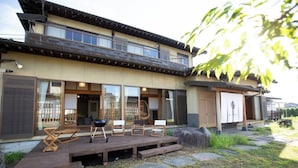 Ein traditionelles japanisches Haus mit einer Holzdiele, Schiebetüren und einem Essbereich mit Gartenmöbeln.