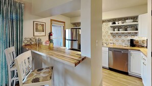 A modern kitchen with a wooden island, white cabinetry, and a stainless steel refrigerator. - Casa Cielo | Great Location + Southwest Condo (Santa Fe)