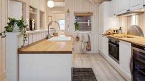 Eine moderne Küche mit Holzausstattung, einer zentralen Kochinsel und einem eingebauten Backofen.