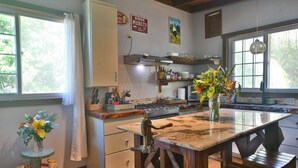 Une cuisine avec une table en bois, une cuisinière à gaz et un luminaire suspendu.