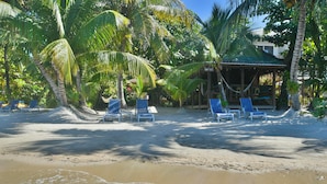 Une plage avec des chaises longues bleues et un petit abri doté d’un hamac.