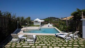 A backyard with a swimming pool, lounge chairs, and a small gazebo. - Clivia- 03 bedroom villa with private terrace (Massa Lubrense)