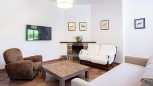 A living room with a fireplace, a flat-screen TV, and framed artwork on the wall. - Clivia- 03 bedroom villa with private terrace (Massa Lubrense)