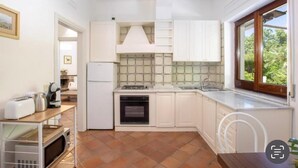 A compact kitchen with white cabinets, a built-in oven, and a window with a view of greenery. - Clivia- 03 bedroom villa with private terrace (Massa Lubrense)