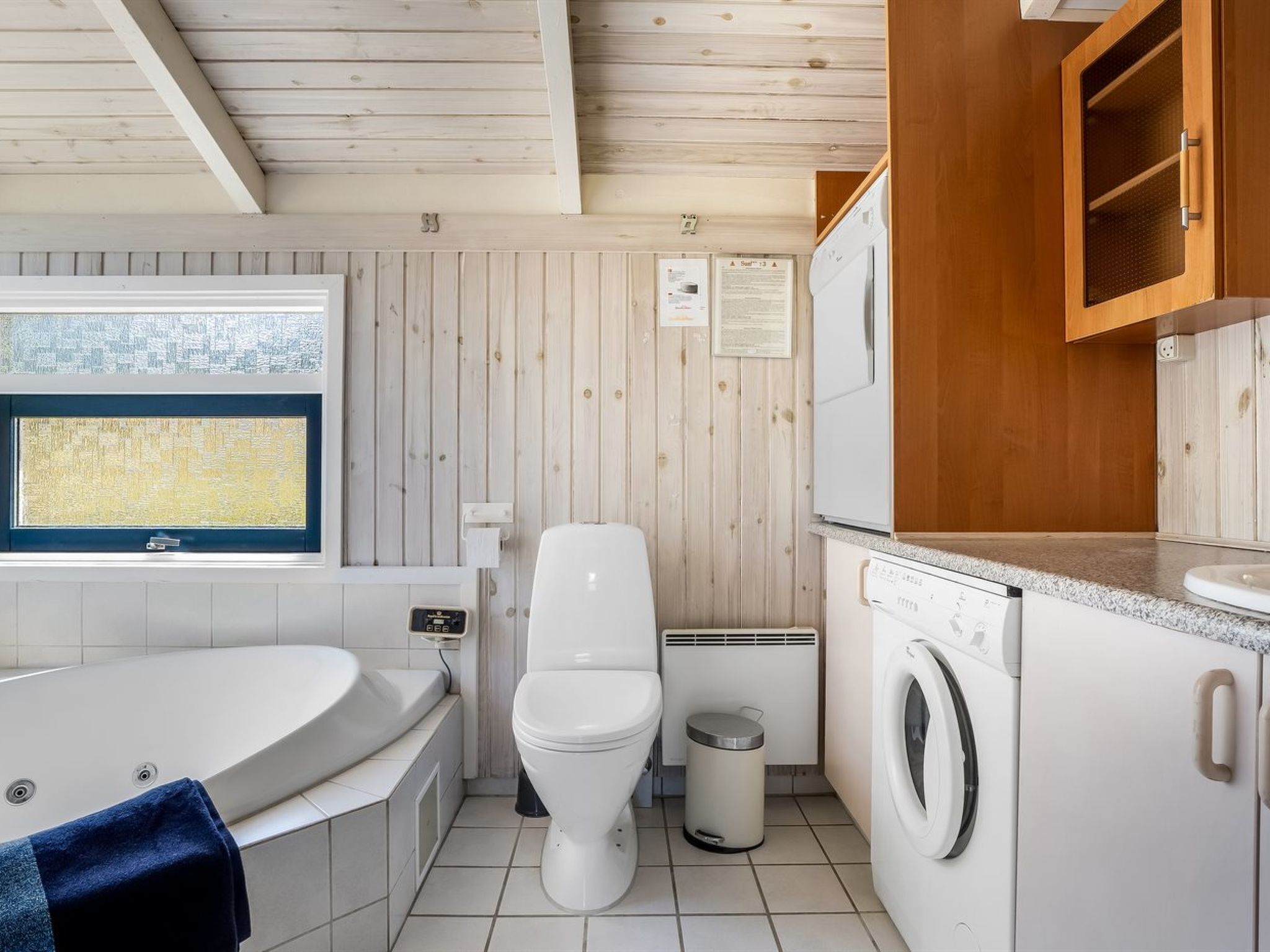 A compact bathroom with a bathtub, toilet, and washing machine.