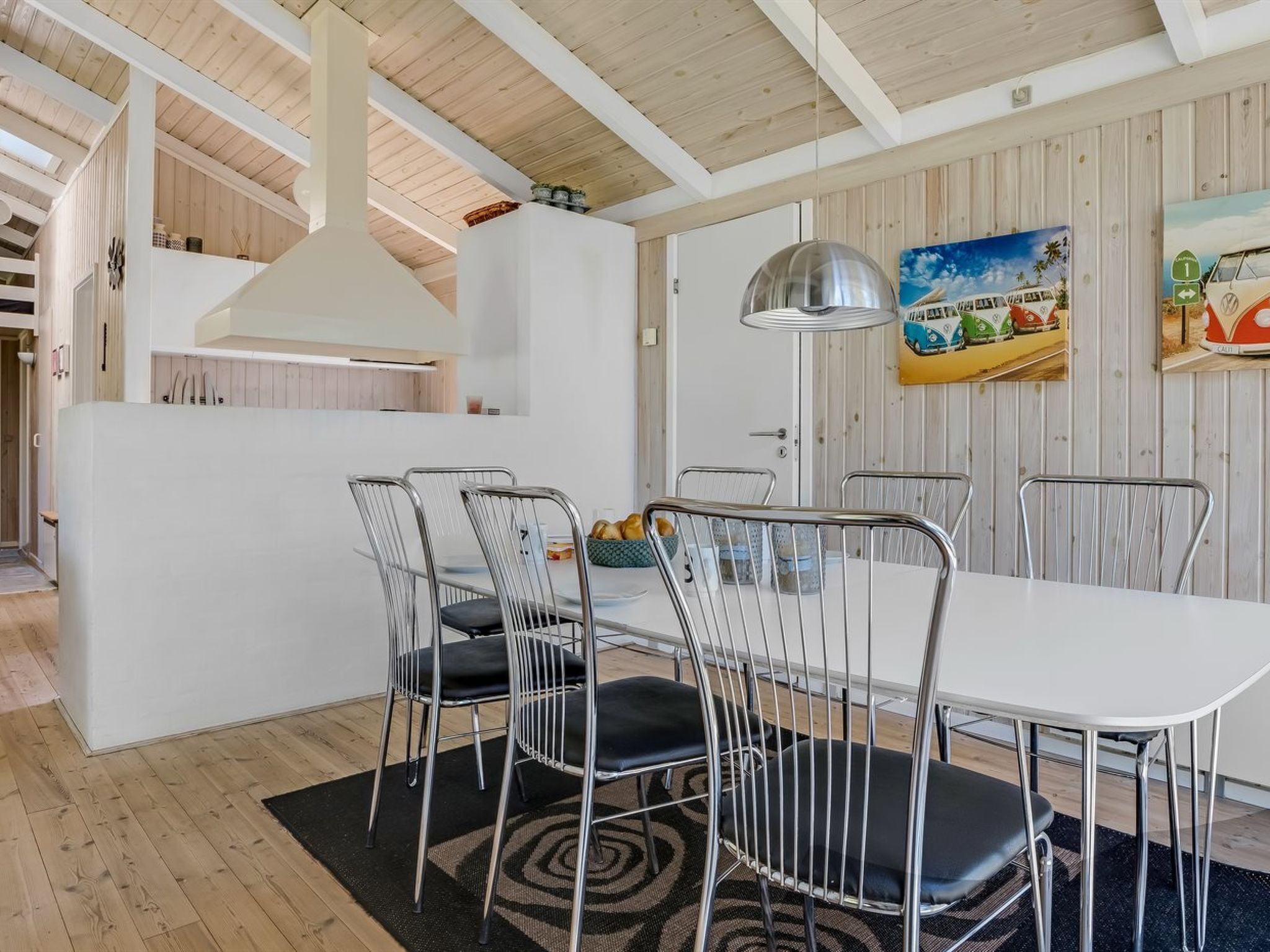 A modern kitchen with white cabinetry, a large island, and a dining area with metal chairs and a white table.