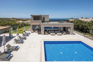 Ein moderner Poolbereich mit Liegestühlen und einem großen Pool mit Blick auf eine malerische Landschaft.