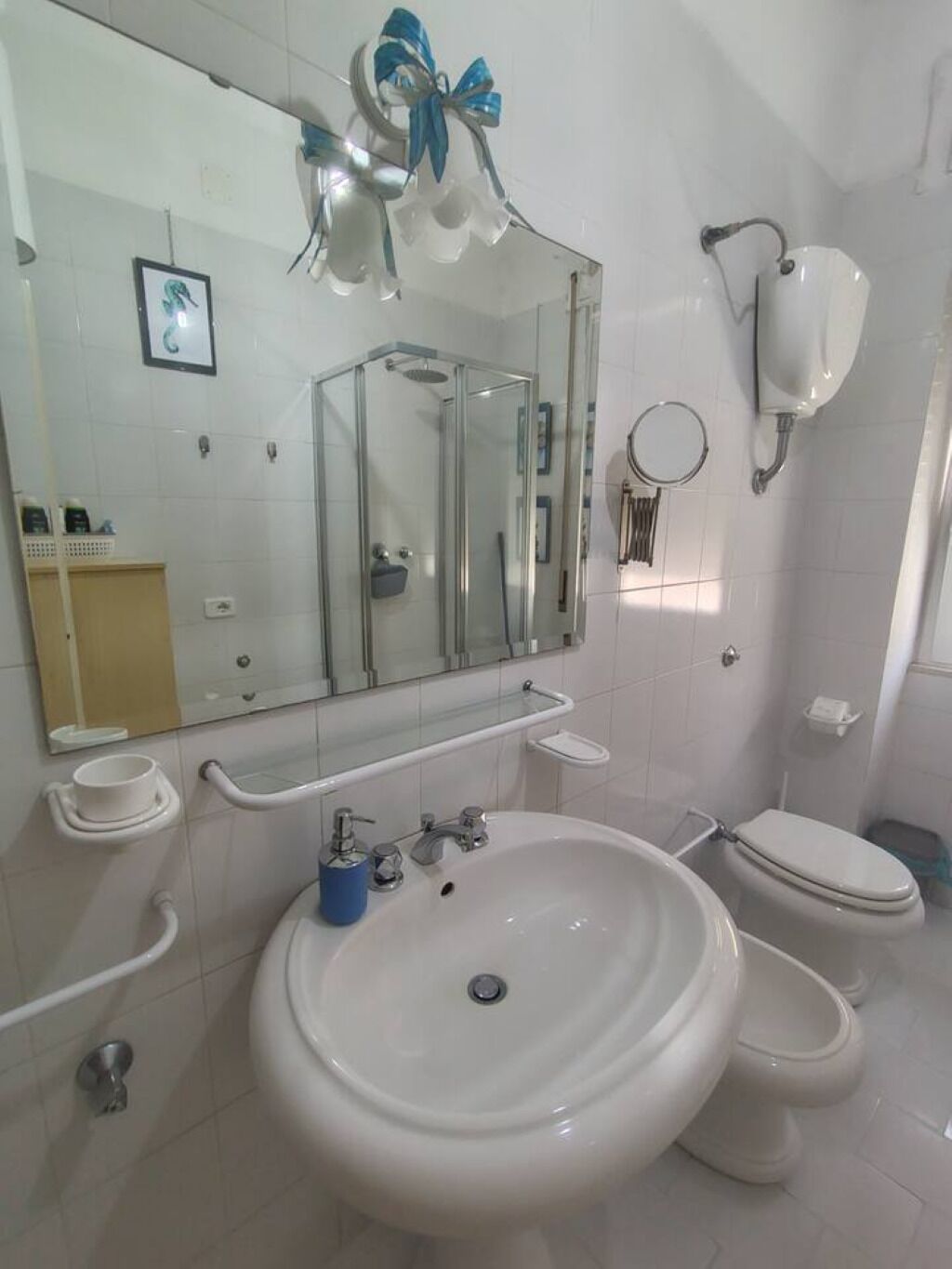 A bathroom with a large mirror, a sink, a toilet, and a shower enclosure.