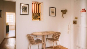 A room with a round table and four chairs, a door with a brass handle, and two framed pictures on the wall. - Saudade Apartment (Lisbon)