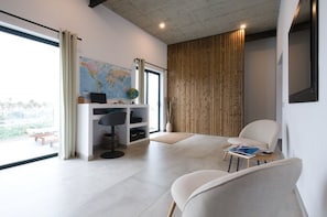 A modern living room with a large window, a map on the wall, a desk with a globe, and a comfortable seating area. - The Langlois House Telde (Telde)