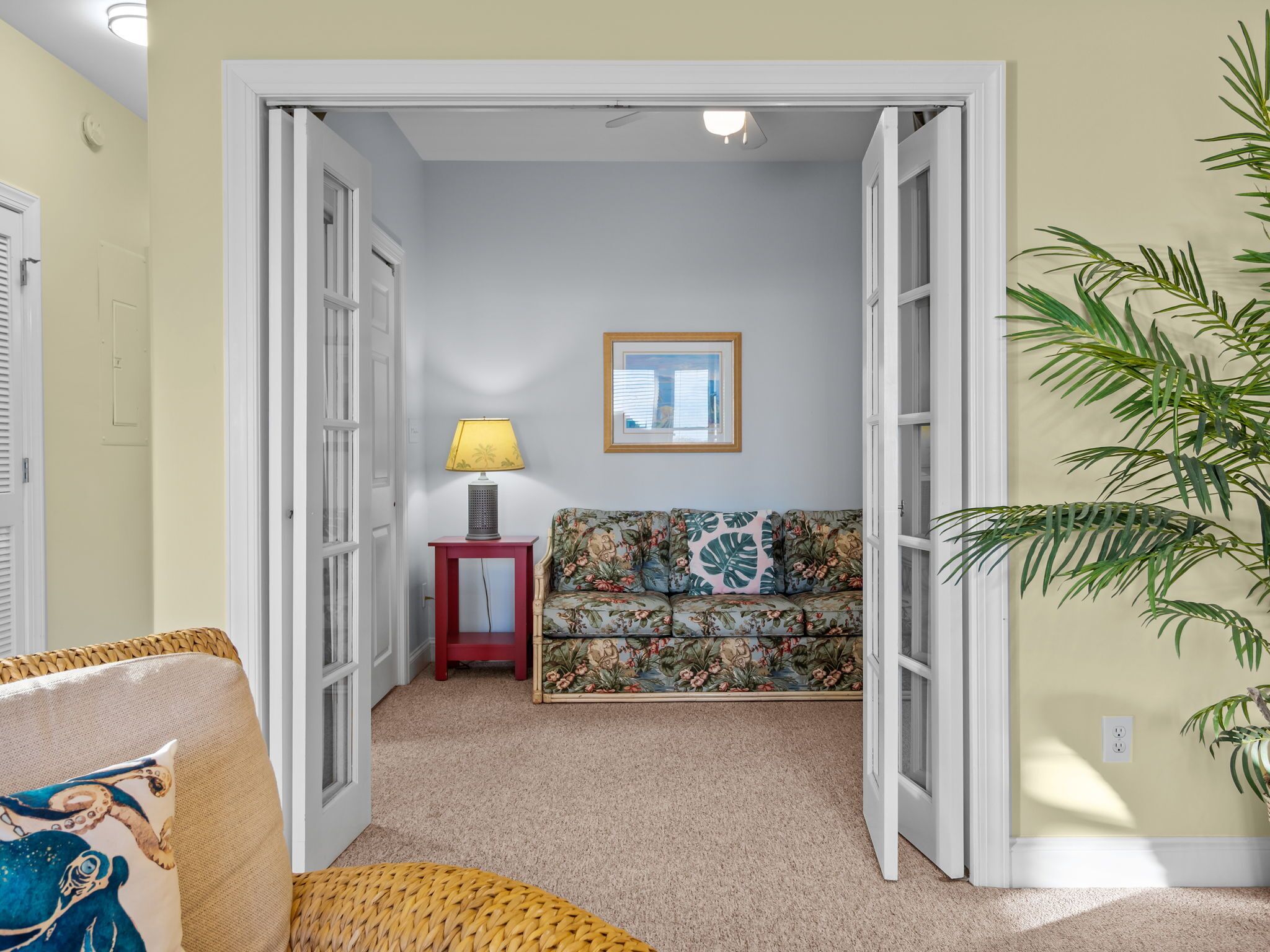 A hallway with a sofa, a lamp, and a plant.