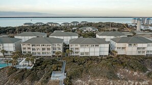 Ett bostadsområde vid kusten med flera tvåvåningsbyggnader, en swimmingpool och utsikt över havet.