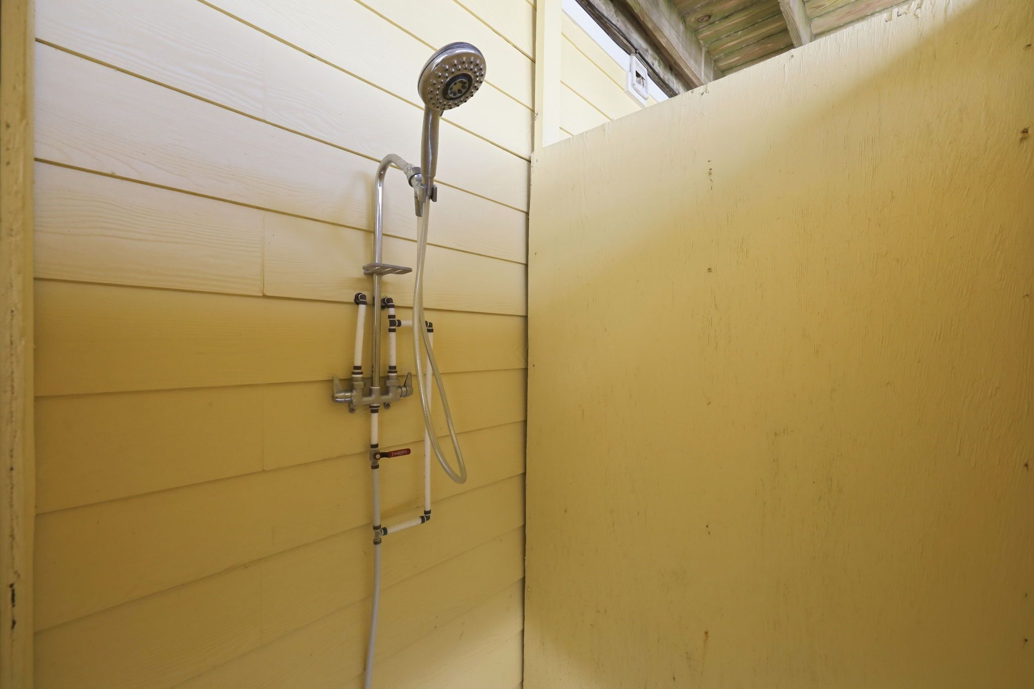 A shower with a handheld showerhead and a handheld hose.