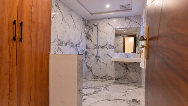Un baño con paredes de mármol y una puerta de madera.