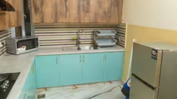 A kitchen with wooden cabinets, a sink, a stove, and a refrigerator. - Cottage 1 (Khaira Gali)