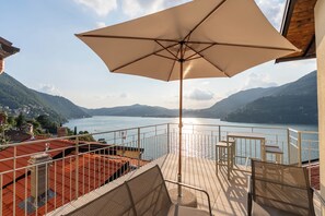 A terrace with a large umbrella, a view of a lake, and a mountainous landscape. - DN ART ROYALE: Villa w/ Private Spa, Hot Tub & Stunning Lake Como View Terrace (Blevio)