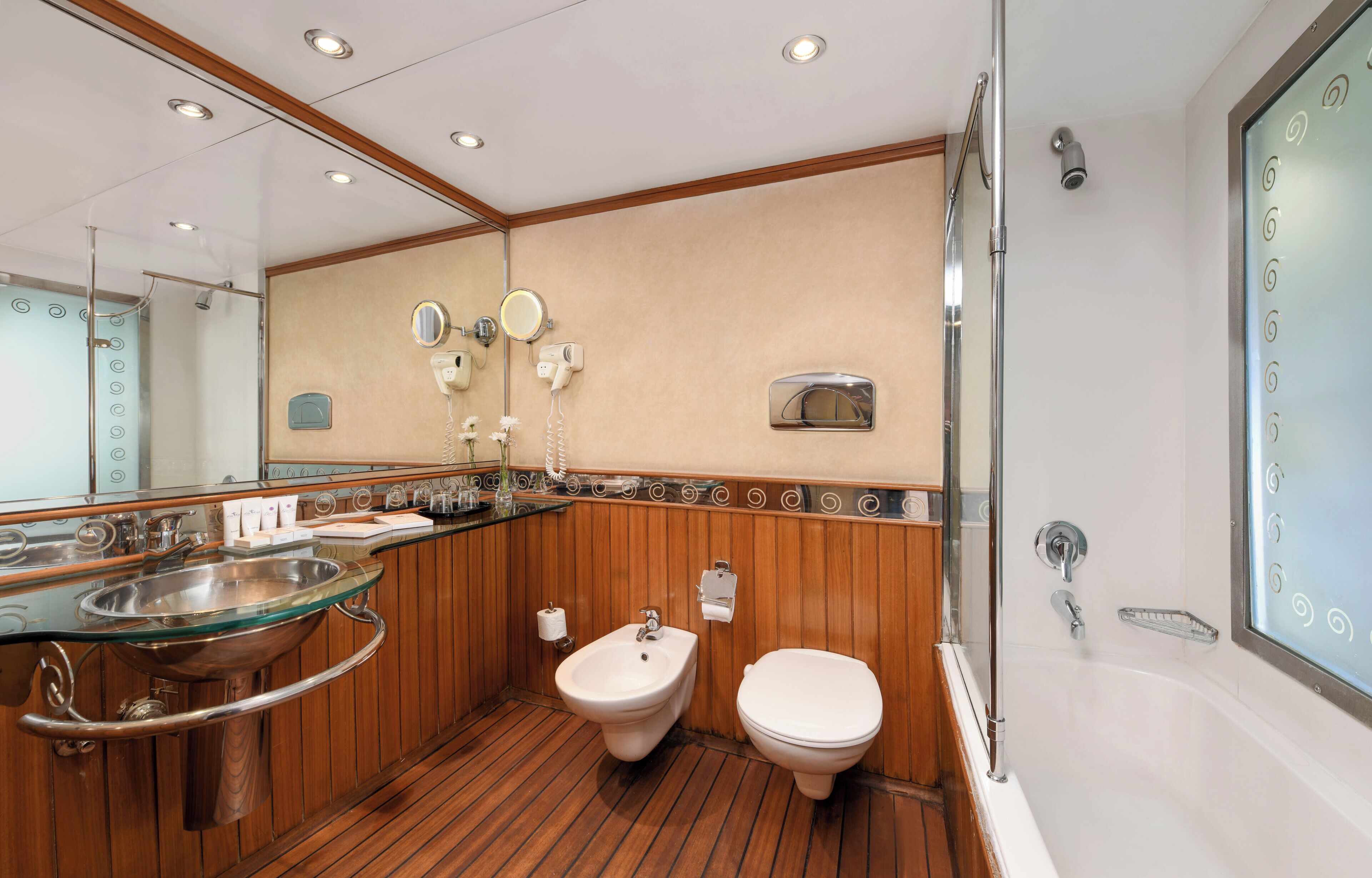 Un baño moderno con lavamanos de vidrio, bidé y bañera.