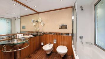 Un baño moderno con lavamanos de vidrio, bidé y bañera.