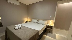 Een hotelkamer met een bed, twee nachtkastjes, een wandairconditioner.