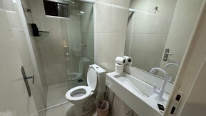Een moderne badkamer met toilet, wastafel en douchecabine met glazen wanden.