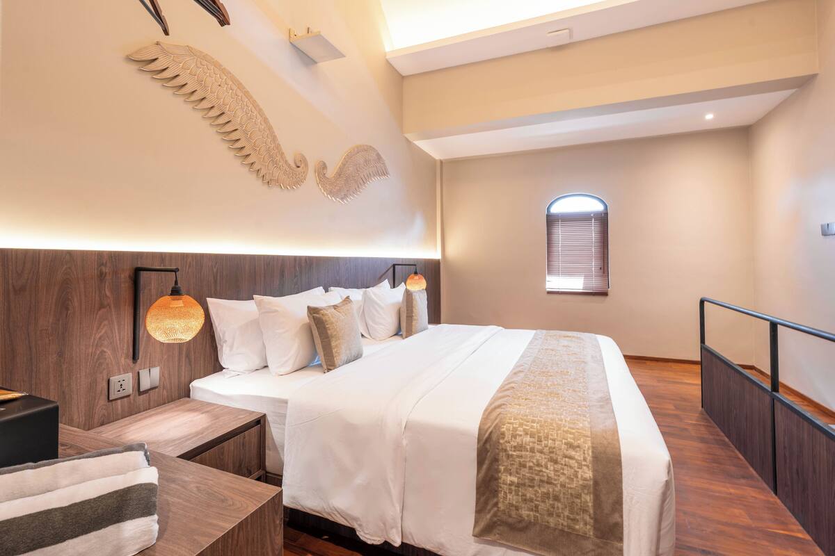 A modern bedroom with a large bed, wooden headboard, and a unique wall decoration.