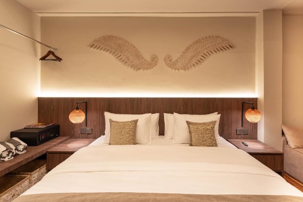A hotel room with a large bed, two bedside tables, a wooden headboard, and a decorative ceiling design.