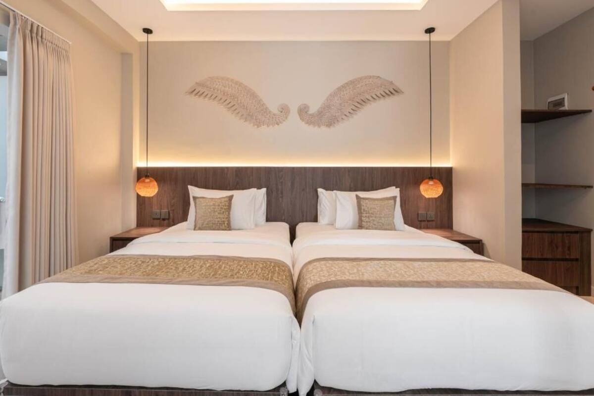 A double bed room with a modern design, featuring a unique wall art of wings, a large window with curtains, and a built-in shelf.