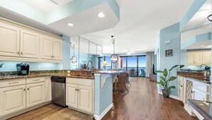 A spacious kitchen with white cabinets, granite countertops, and a central island. - Unit 0702E a beautiful 2 bedroom and 2 bath unit (ORANGE BEACH)