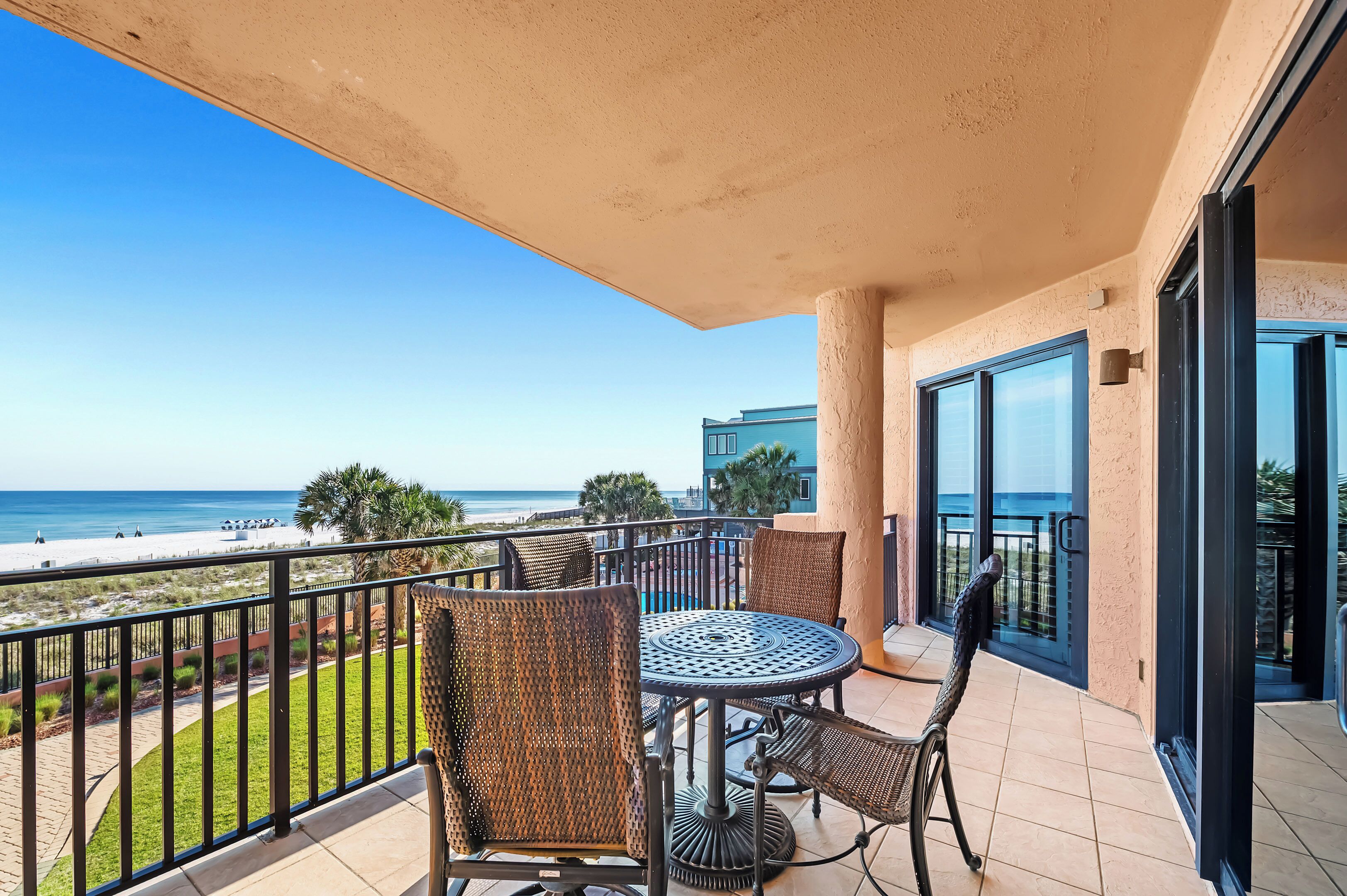 Ein Balkon mit Tisch und Stühlen mit Blick auf Strand und Meer.
