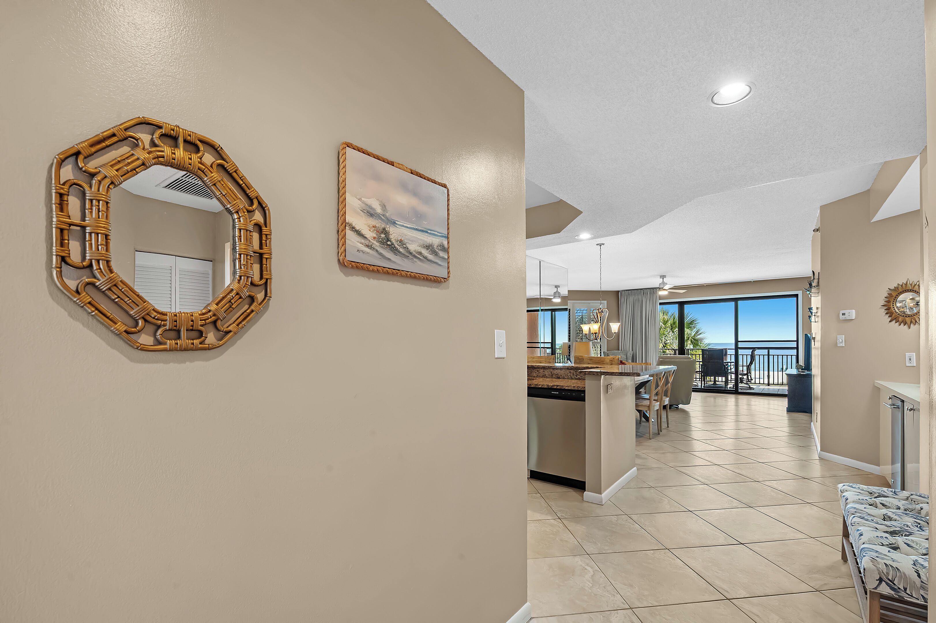A spacious living area with a large mirror, a painting, and a view to a balcony.